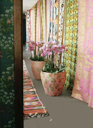 Bohemiskt vardagsrum med flera Phalaenopsis (brudorkidĂ©) i fĂ€rgad kruka pĂ„ golvet, varma toner i rött, rosa och gult â höst och vinter inredning och stylingtips