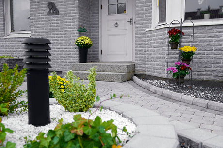 Trädgårdsdesign med svängd gång av långsmala stenar och trampstenar mot terrass; landskapsarkitekt, trädgårdsanläggare, slittåliga plattor, hållbar utemiljö.