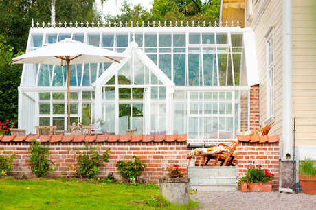 Conservatory-inspirerat vĂ€xthus/uterum i Hjo vid VĂ€ttern â Hartley Botanic Victorian Lodge frĂ„n Vansta TrĂ€dgĂ„rd, integrerat med boningshus, kalkstensgolv, tegelmur och franska dörrar.