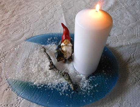 Stämningsfullt snölandskap med tomte och batteriljus på blåskimrande glasfat – konstsnö, lavbevuxen gren och julpynt för mysig, säker dekoration.