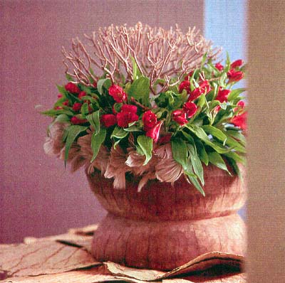 Alstroemeria arrangerad runt en torr kvist i rustik träskål med mjuka fjädrar – höstens blomstertrend Landscape från Blomsterfrämjandet; naturnära, texturrik design med torkade växtdelar, organiska former och dämpad nordisk färgskala.