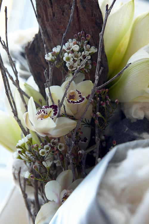 Närbild av naturnära bukett i jordnära färger med protea (Protea), krysantemum (Dendranthema x grandiflorum) och amaryllis (Hippeastrum) i enkel, rustik vas – snittblommor med torkade inslag för hållbar, återbrukad inredning med naturliga material.