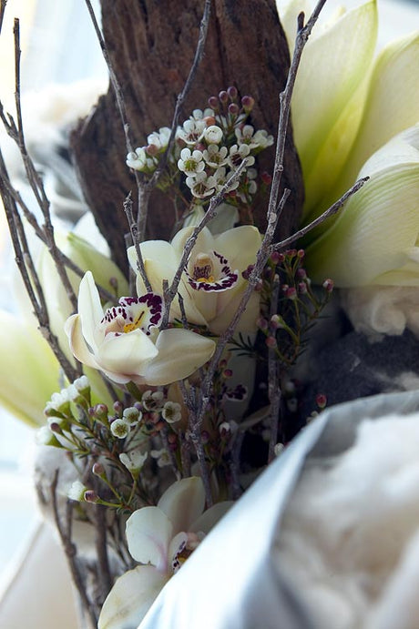 Närbild av naturnära bukett i jordnära färger med protea (Protea), krysantemum (Dendranthema x grandiflorum) och amaryllis (Hippeastrum) i enkel, rustik vas – snittblommor med torkade inslag för hållbar, återbrukad inredning med naturliga material.
