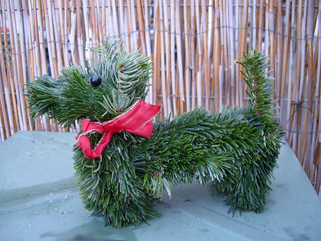 Swedish December tradition: granhund (spruce dog) crafted from evergreen branches with white fairy lights—tasteful Advent and Christmas (Jul) decoration for the winter garden.