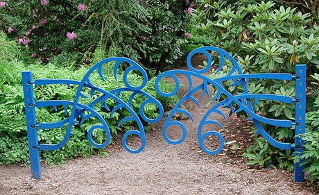 Blå skulptural grind i konstsmide av Åge Ørsland med figurer i rörelse – utställning i Göteborgs botaniska trädgård (HDK Steneby); metalldesign som symboliserar gräns, passage och mötesplats.